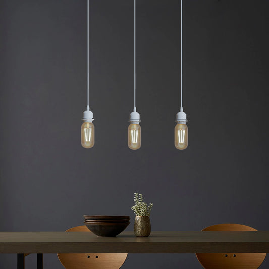 White pendant light fittings with vintage filament bulbs suspended above a dining room table in a modern interior