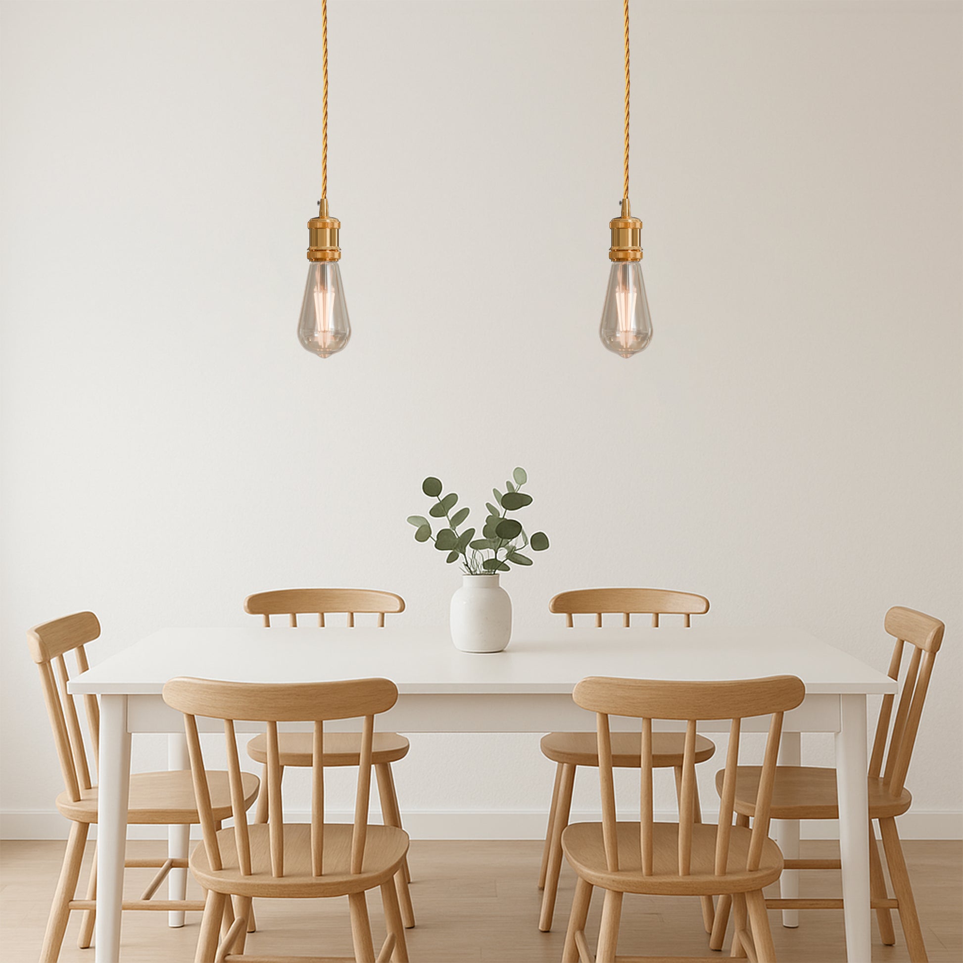 Two French gold pendant lights with twisted fabric cables and bulbs, hanging above a  dining table
