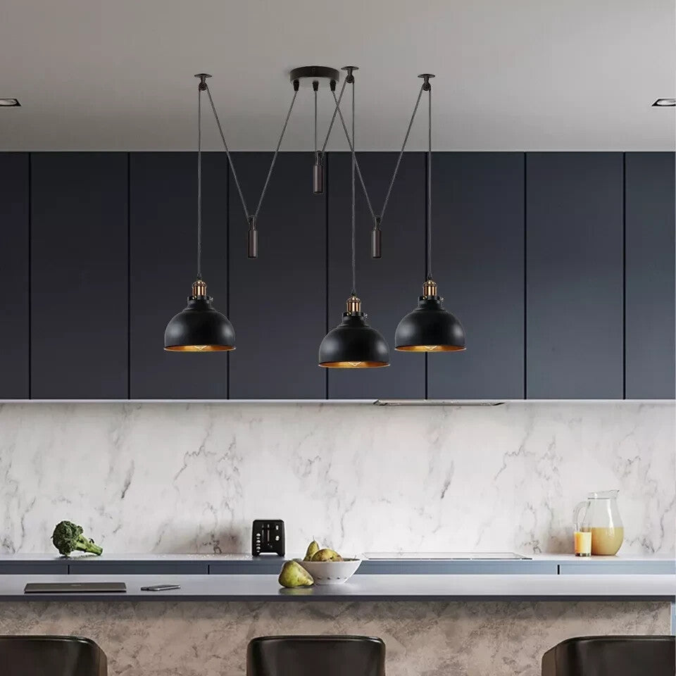 Modern kitchen with black pendant lights, marble countertop, and gray walls.