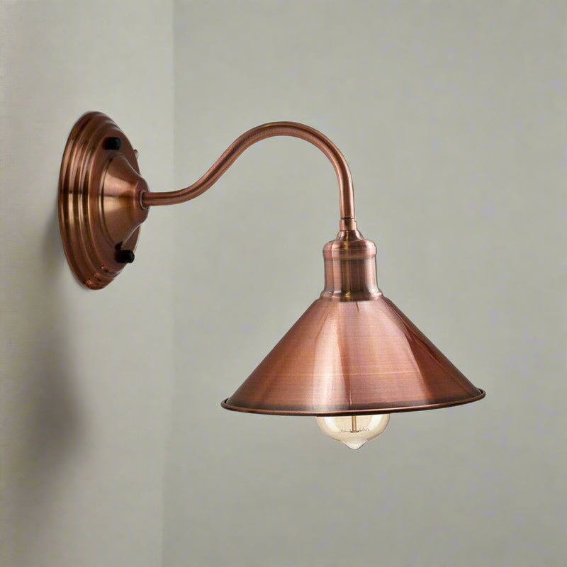 A copper wall-mounted sconce with a cone-shaped lampshade and an exposed bulb, providing a warm light.