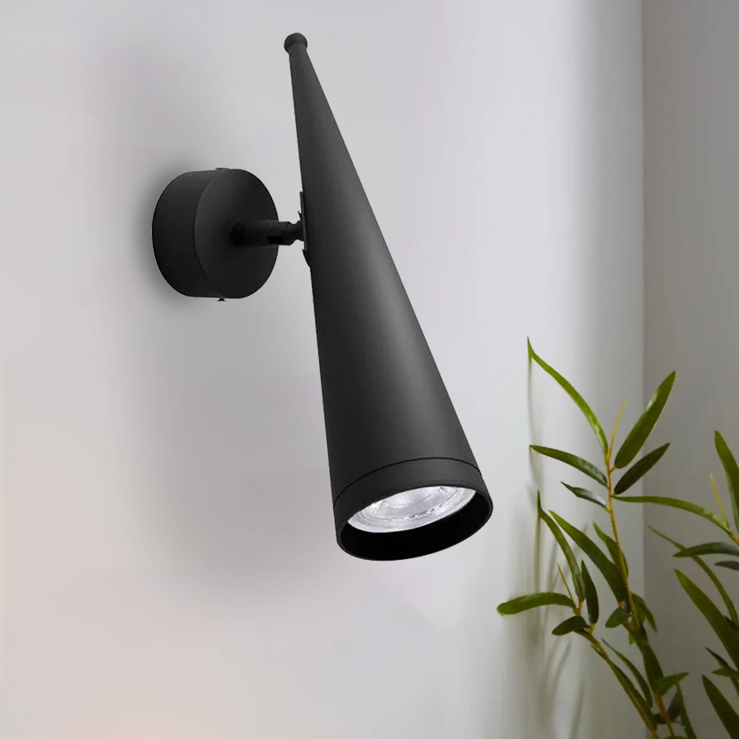 A modern LED black cone shade wall lamp with a GU10 bulb base, mounted on a wall and displaying a cone-shaped light beam.