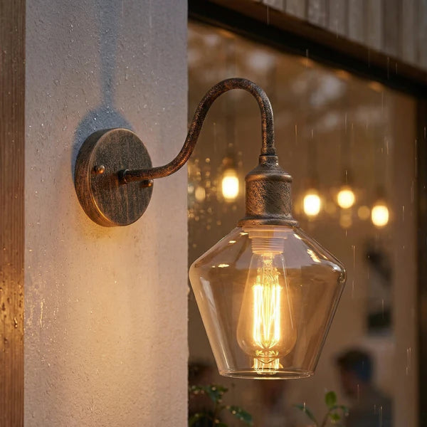 Vintage-style wall light fixture with a glowing bulb on a textured wall.