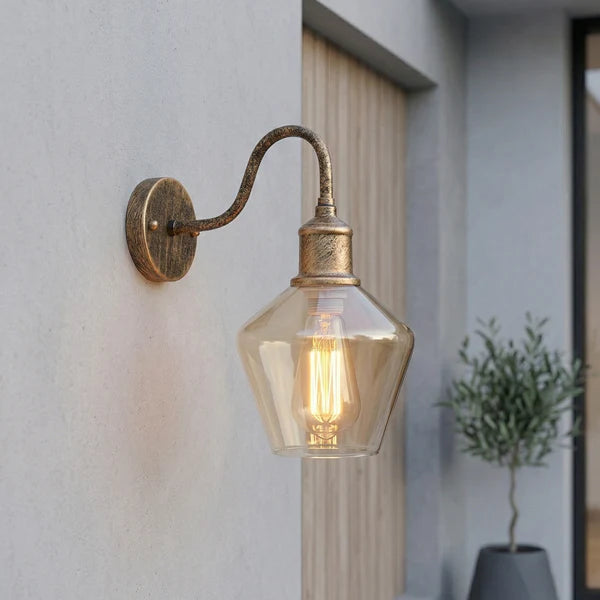 Vintage-style Fovant wall light fixture on a wall with a plant in the background