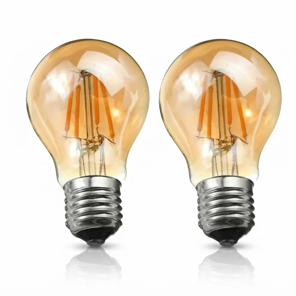 Two vintage-style LED filament light bulbs with clear glass and warm amber tones, shown side by side on a white background with soft reflections below.