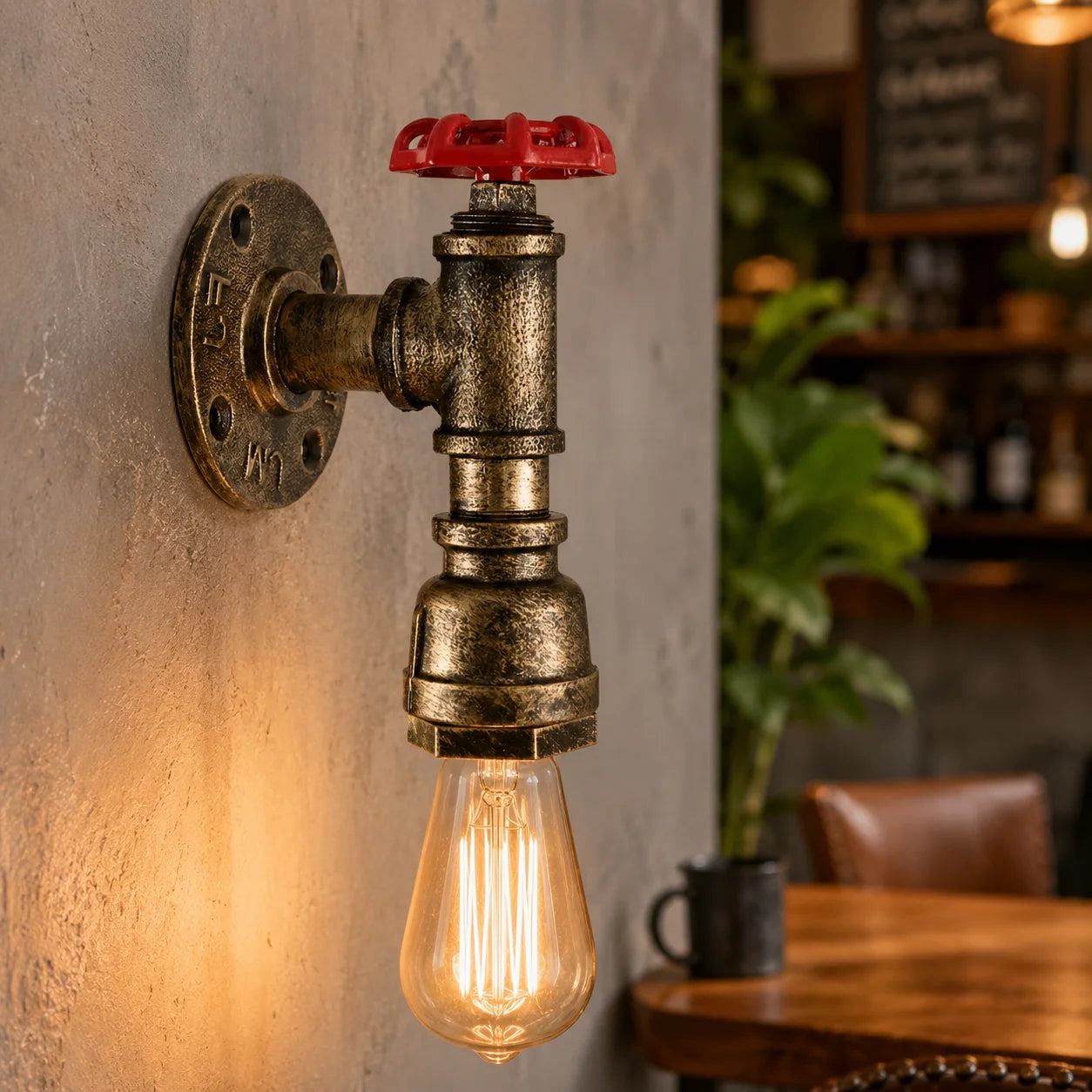 Wall-mounted industrial-style light fixture with a red valve handle, glowing bulb, and blurred cafe interior.