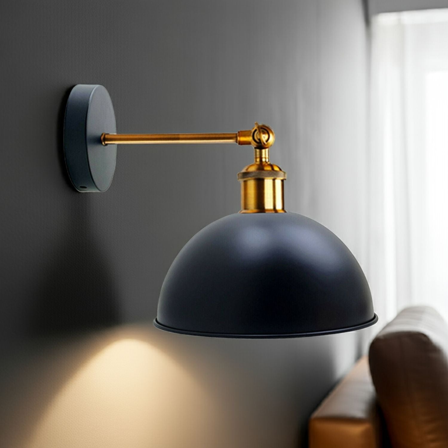Wall-mounted lamp with black shade and gold arm on a gray wall.